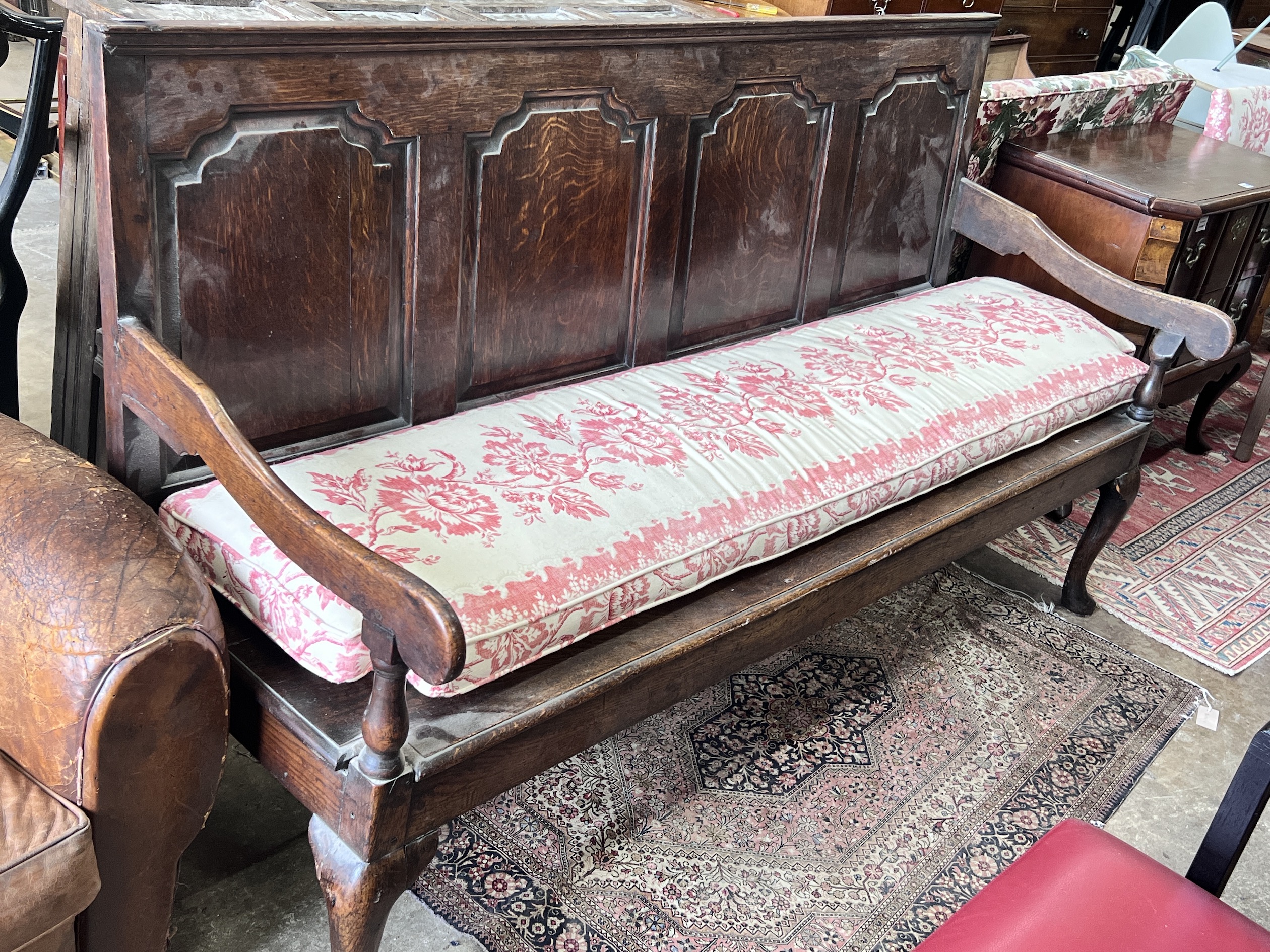 An 18th century panelled oak settle with squab seat, length 184cm, depth 63cm, height 105cm